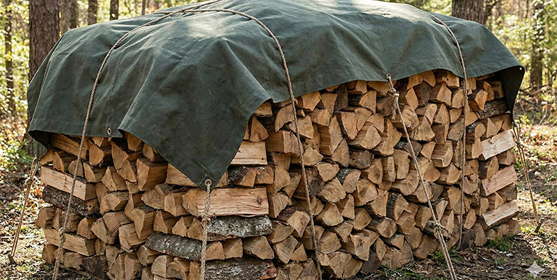 Правилно покрито дърво за огрев с брезент, позволяващ циркулация на въздуха